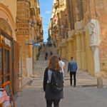woman in black coat standing on sidewalk during daytime
